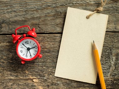 Kırmızı kalem ahşap rustik masanın üzerine yazmak için çalar saat not defteri