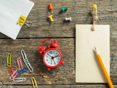 Kırmızı kalem ahşap rustik masanın üzerine yazmak için çalar saat not defteri