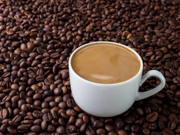 Taza de café con leche en el fondo de granos de café — Foto de Stock