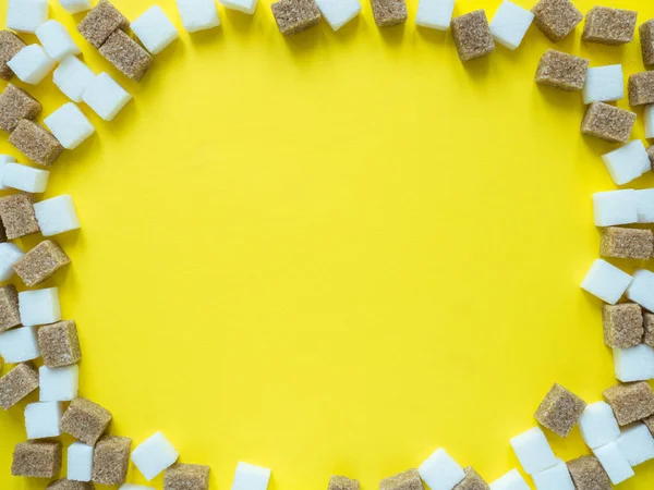 Cubos de açúcar branco e mascavo sobre fundo amarelo — Fotografia de Stock