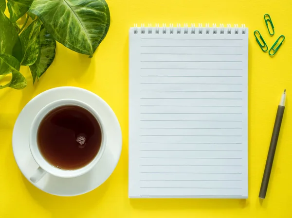 Σημειωματάριο για σημειώσεις, πράσινα φύλλα φυτού Καφές Κύπελλο στην κίτρινη επιφάνεια εργασίας, επίπεδη θέσει, αντίγραφο χώρου. — Φωτογραφία Αρχείου