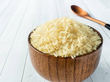 Kaynatılmış pirinç kabuğu çıkarılmış tane hafif bir arka plan üzerinde bir ahşap kase