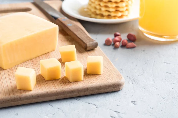 Healthy Breakfast Cheese on a Board cut into cubes Juice Peanuts waffle Cookies Selective focus. — Stock Photo, Image