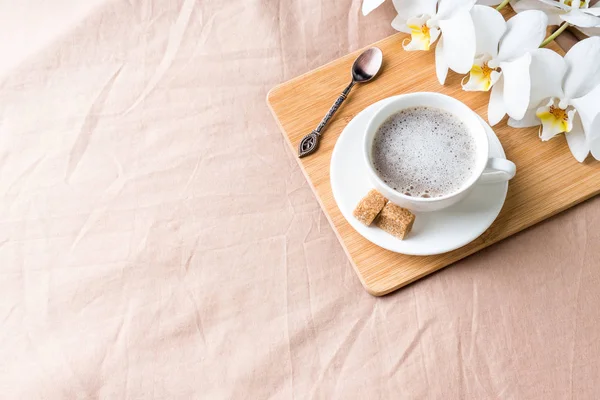 Acogedora composición con una taza de café en una bandeja con azúcar en una manta de café pastel . — Foto de Stock