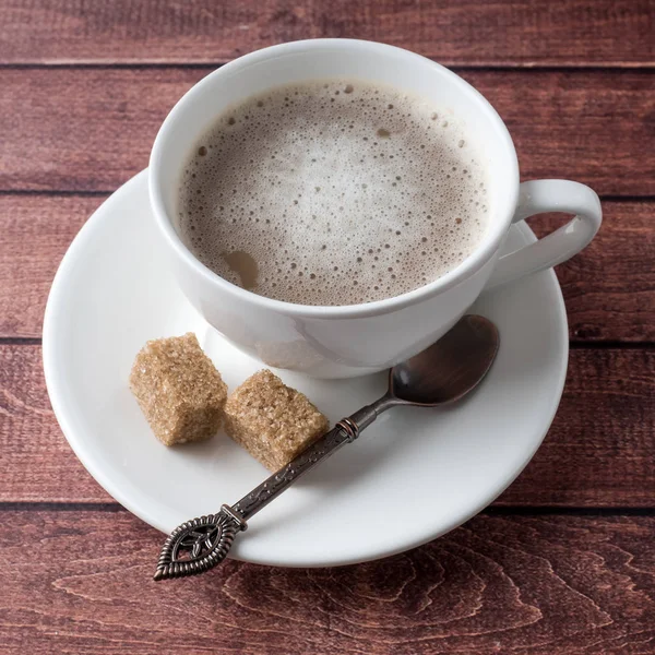 Copa blanca y platillo de café con espuma de leche y azúcar de caña de canela anís — Foto de Stock