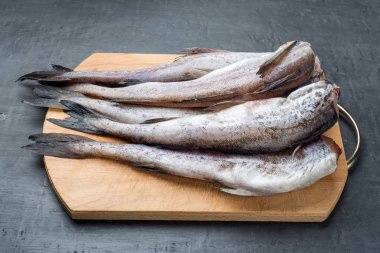 Koyu arka plan üzerinde ahşap kesim tahtası üzerinde köle çiğ balık