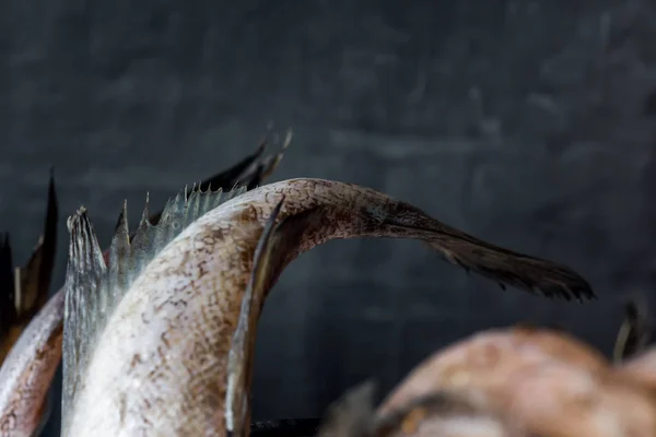 Tails of raw fish on dark background. Selective focus