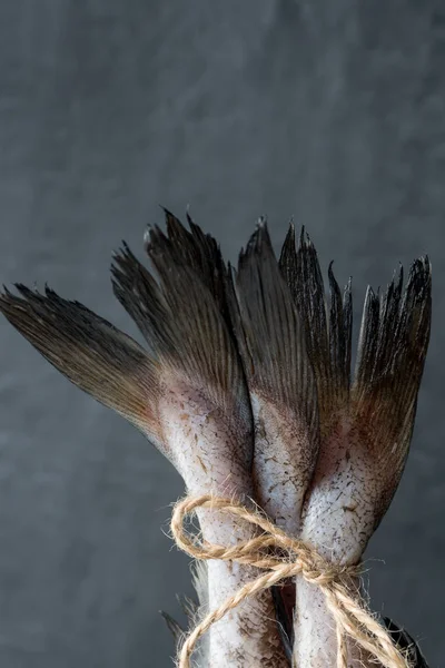 Raw fish tails tied with rope with bow on dark background. Selective focus — Stock Photo, Image