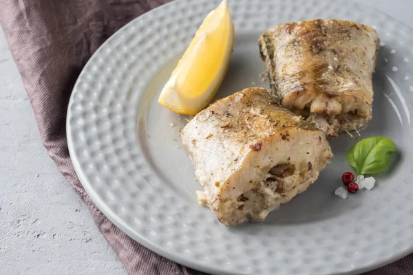 Запечённая рыба Поллок с лимоном и специями на тарелке Салфетка на столе — стоковое фото