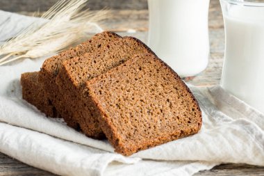 Cam bardak ve dilimlenmiş tahıl ekmek ahşap rustik arka plan üzerinde taze sağlıklı süt