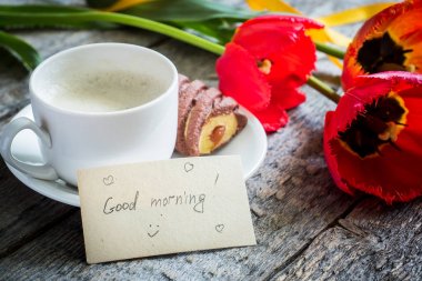 Ahşap bir masa üzerinde üç renkli Lale. Kahve, kurabiye. Atmosferik ruh hali. Kahvaltı