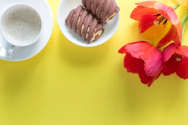 Flores rojas de tulipanes sobre fondo amarillo brillante. Copia espacio para texto. Copa de café, galletas caseras — Foto de Stock