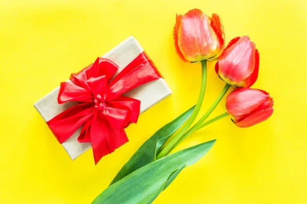 Caja de regalo con lazo rojo flor ramo tulipanes sobre fondo amarillo brillante —  Fotos de Stock