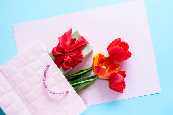 Geschenkbox mit rotem Band Strauß von Tulpen in rosa Paket auf zartem Pastell Hintergrund — Stockfoto