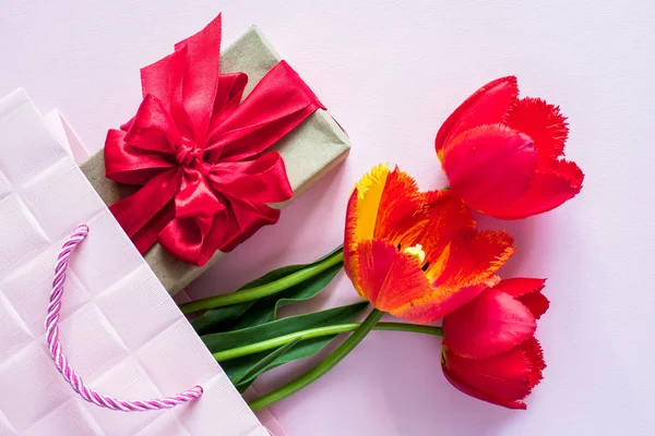 Geschenkbox mit rotem Band Strauß von Tulpen in rosa Paket auf zartem Pastell Hintergrund — Stockfoto