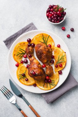 Portakallı tavuk budu ve gri bir tabakta kızılcık. Süslü Noel yemeği masası. Boşluğu kopyala.