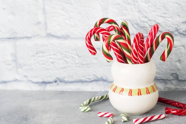 Lots of Christmas candy canes in a mug on a grey background with copy space. Bright festive Christmas caramel. — 스톡 사진