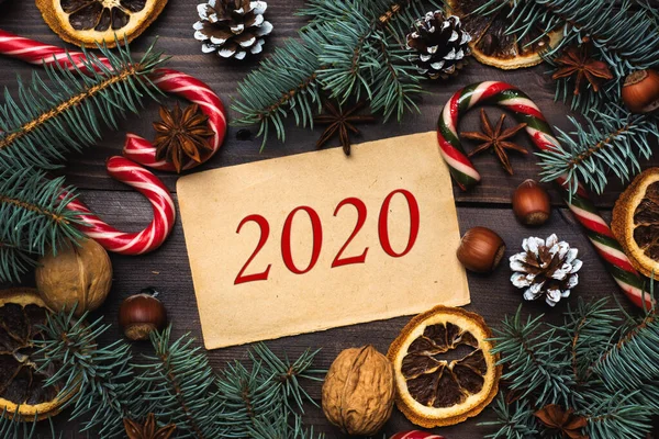 Noel ağacı konilerinin çerçevesi koyu ahşap arka planda karamel kamışlı fındıklar. Yazıt 2020.