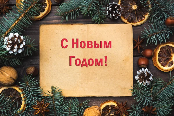 Ramen av julgran kottar apelsiner nötter på mörka trä bakgrund. Inskriptionen på ryska Gott Nytt År. — Stockfoto
