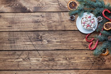 Marşmelovlu bir fincan sıcak çikolata. Noel ağacı ve süslemeler, karamel kamışı ve portakallar ahşap arka plan kopyalama alanı.