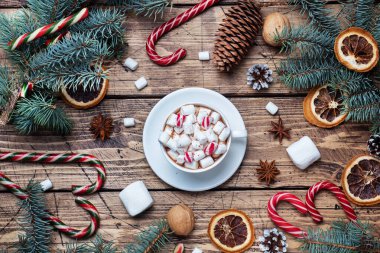 Marşmelovlu bir fincan sıcak çikolata. Noel ağacı ve süslemeler, karamel ve portakallar ahşap arka plan