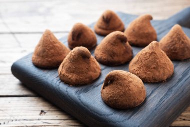 Tahta bir standın üzerine kakao tozu serpiştirilmiş lezzetli çikolatalı trüf. Ahşap arka plan. Boşluğu kopyala.