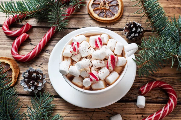 Une tasse de chocolat chaud avec des guimauves. Arbre de Noël et décorations, caramel de canne et oranges noix Fond en bois — Photo