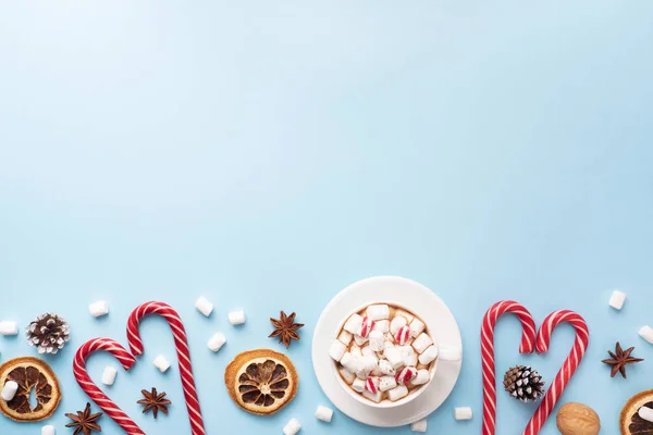 Tazza di cioccolata calda con marshmallow cacao in polvere e noci caramello, arance su sfondo blu pastello con spazio copia. Natale inverno concetto . — Foto Stock