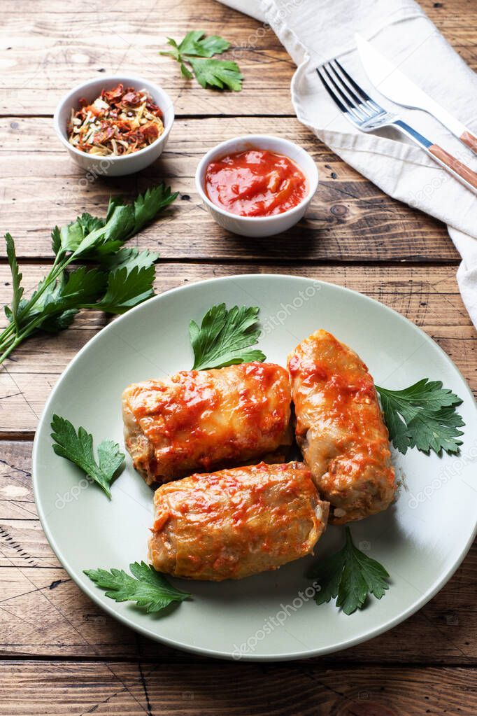 Cabbage rolls with beef, rice and vegetables on the plate. Stuffed cabbage leaves with meat. Wooden background.