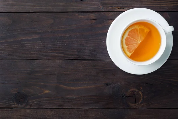 Λευκό Κύπελλο με φυσικό τσάι βοτάνων με κανέλα λεμονιού. Το ζεστό βιταμινούχο ποτό χρησιμοποιείται για κρυολογήματα. Σκούρο ξύλινο χώρο αντιγραφής φόντου. — Φωτογραφία Αρχείου
