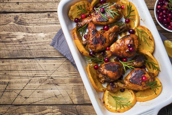 Gebackene Hähnchenbrust mit Orangen und Preiselbeeren in einem Backblech auf einem hölzernen Hintergrund. Weihnachtstisch mit Dekoration. Kopierraum. — Stockfoto