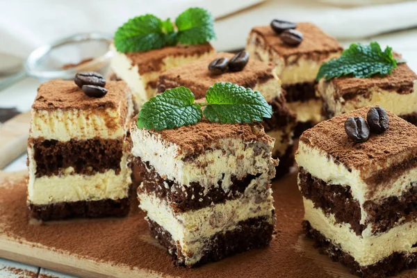 Trozos de tarta de tiramisú con delicada crema, granos de café y hojas de menta . —  Fotos de Stock