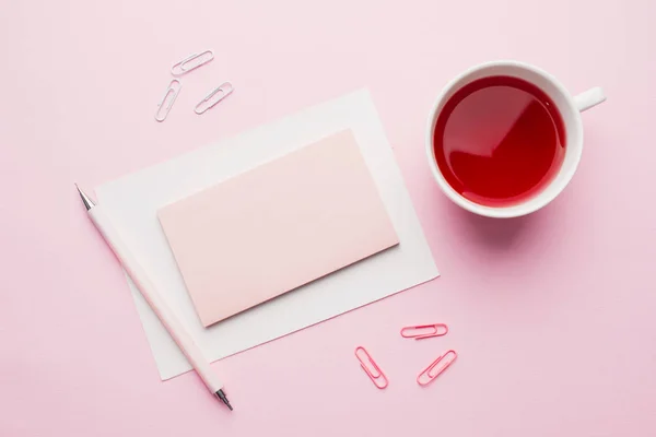 Objetos de color rojo-rosa. Taza de té y bloc de notas para texto sobre fondo rosa pastel. Copiar espacio. Vista superior Plano lay — Foto de Stock