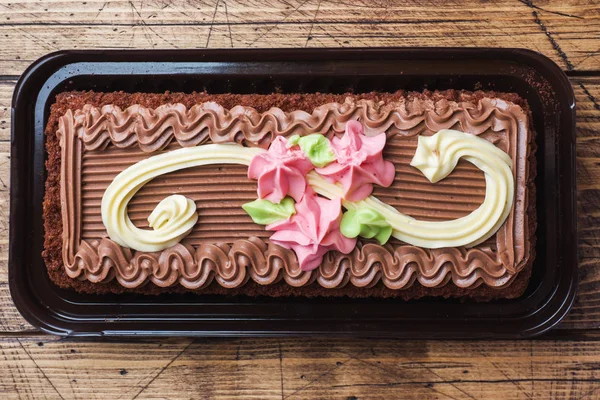 Pastel rectangular de chocolate decorado con rosas crema. La comida dulce es un negocio de confitería. Vista superior — Foto de Stock