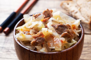 Ahşap bir arka planda ahşap bir kasede etli haşlanmış lahana. Geleneksel Rus yemeği Solyanka.