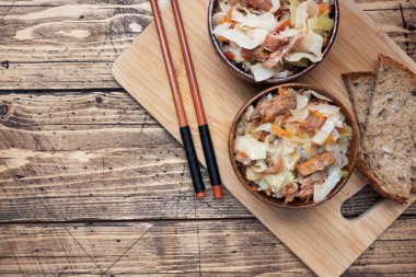 Ahşap bir arka planda ahşap bir kasede etli haşlanmış lahana. Geleneksel Rus yemeği Solyanka. Boşluğu kopyala