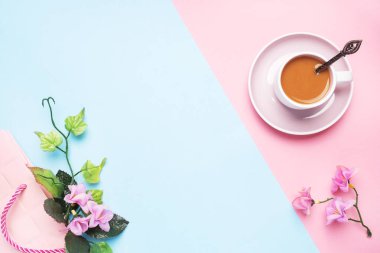 Sütlü bir fincan kahve ve çiçek ve yapraklı bir dal. Fotokopi alanı olan pembe bir pastel arka planda. Düz yatıyordu.