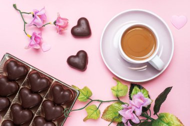 Sevgililer Günü kavramı. Çikolatalı şekerler ve kahve, pembe arka planda kalpler. Düz kopya alanı. Tebrik kartı ve hediye..