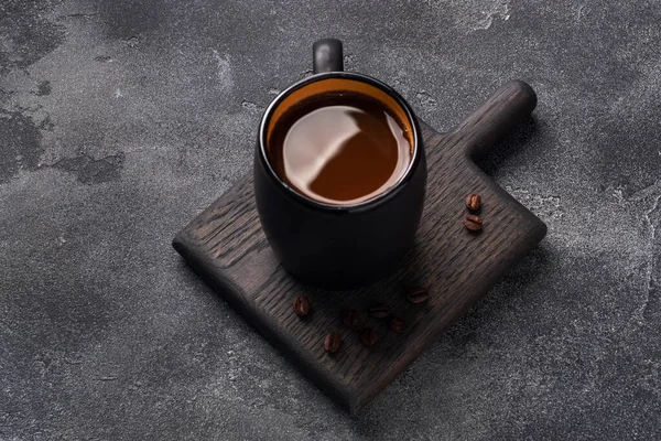 Caffè nero in una tazza e chicchi di caffè su uno sfondo scuro. Vista dall'alto Copia spazio. — Foto Stock