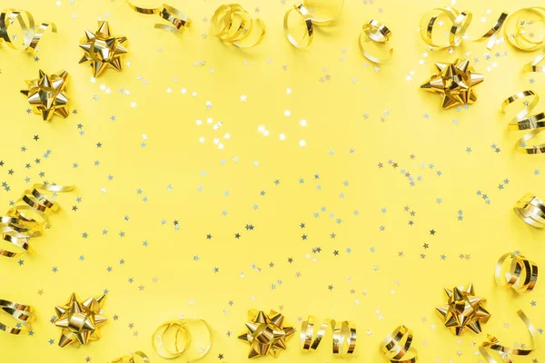 Gold confetti stars and ribbons on a yellow background. Copy space Flat lay. Greeting card for birthday party, Christmas Wedding mother\'s Day.