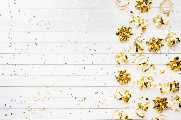 Gold confetti stars and ribbons on a White background. Copy space Flat lay. Greeting card for birthday party, Christmas Wedding mother\'s Day.