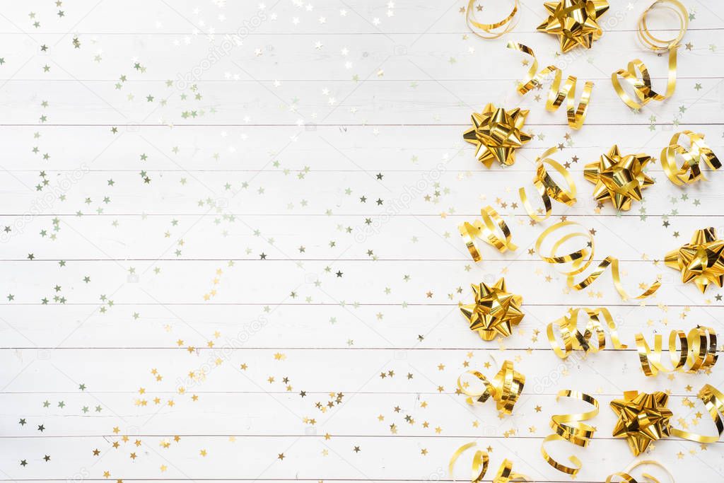 Gold confetti stars and ribbons on a White background. Copy space Flat lay. Greeting card for birthday party, Christmas Wedding mother's Day.