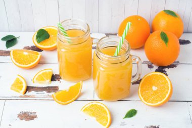 Cam Kavanoz ve Beyaz ahşap rustik zemin üzerine taze portakal portakal suyu.