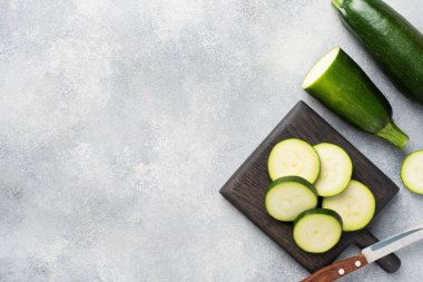 Kesme tahtasında dilimlenmiş taze yeşil kabak. Somut gri arka plan. Boşluğu kopyala.