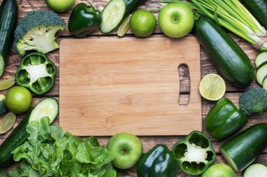 Ahşap bir arka planda taze yeşil sebzeler ve otlar çerçeveletin. Boşluğu kopyala.