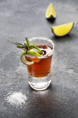 Koyu beton arka planda alkol, tuz ve kireç dolu bir bardak. Konyak viski tekila. Partinin konsepti. Seçici odaklanma. Boşluğu kopyala.