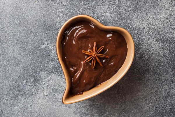 Chocolate paste with cinnamon and anise. Fondue with chocolate on a dark concrete table. copy space