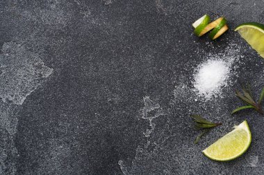 Taze limon dilimleri, tuz ve biberiye koyu beton arka plan. Uzayı kopyala Tekila kokteyli yapmak için gerekli malzemeler.