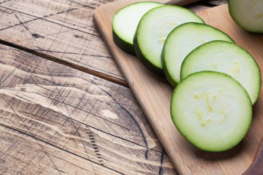 Kesme tahtasında dilimlenmiş taze yeşil kabak. Ahşap kırsal masa arka planı. Boşluğu kopyala