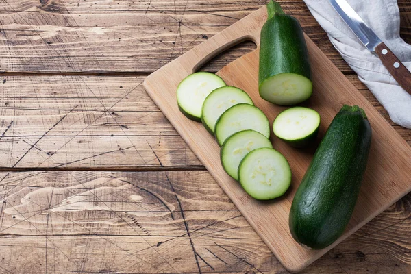 Fresh green zucchini cut into slices on a cutting Board. Wooden rustic table background. Copy space